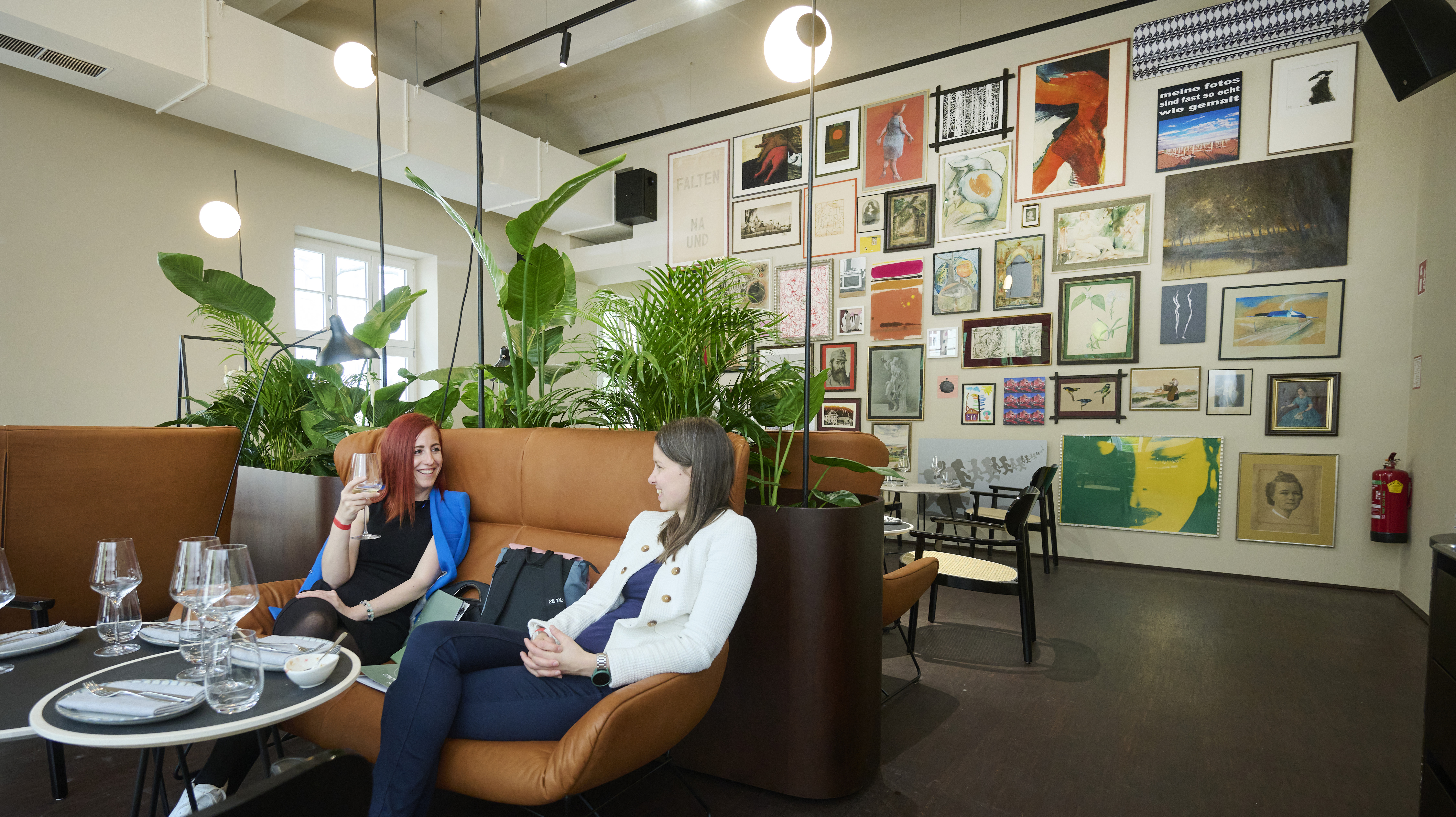 Lounge in der Bel Etage mit Bilderwand, Pflanzen und Sofas