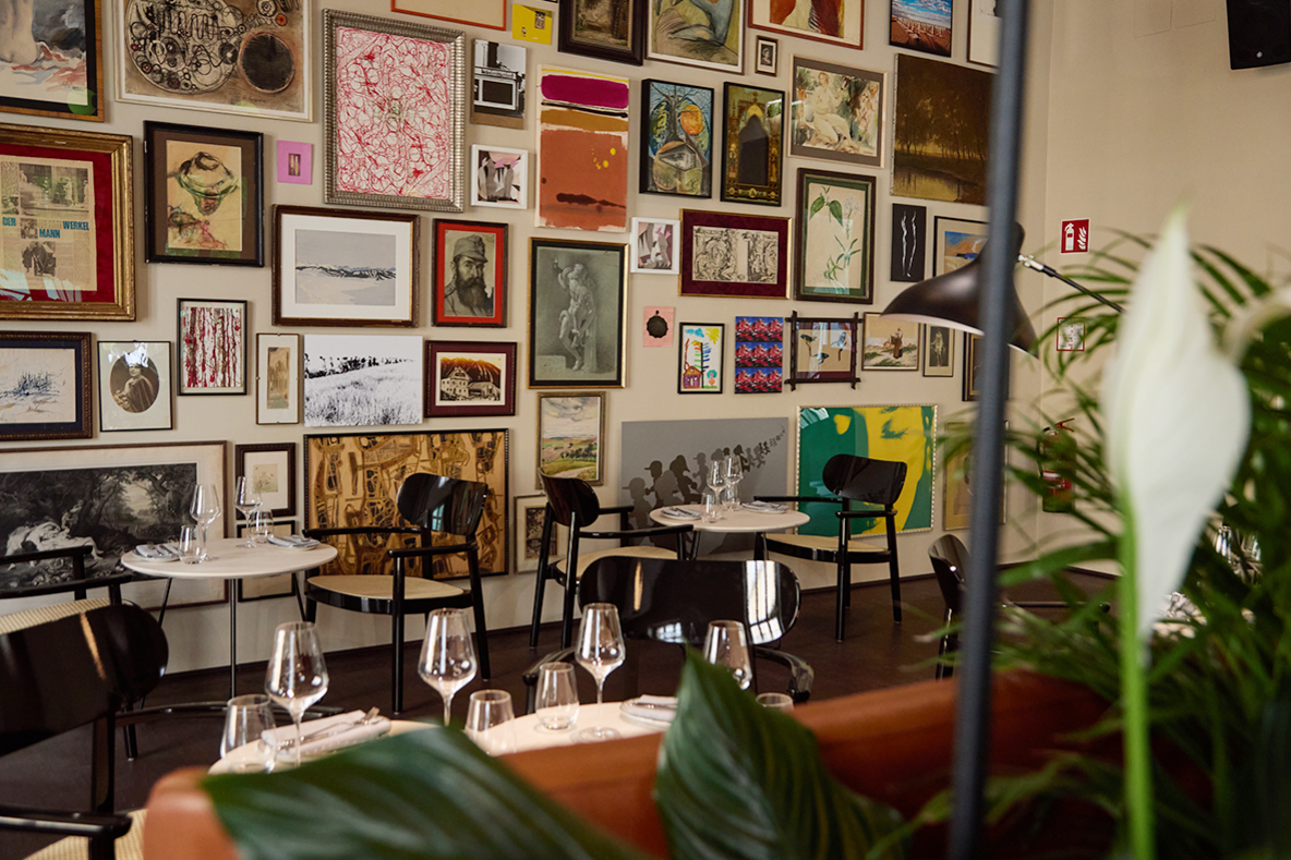 Restaurant des sophie7 mit Bilderwand und gedeckten Tischen