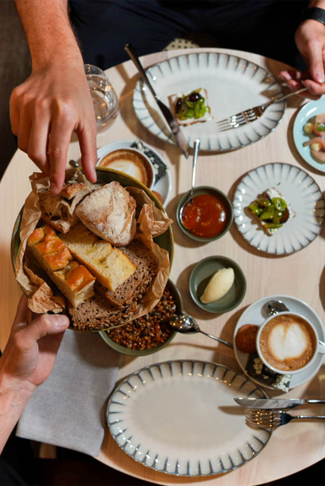 Brunch-Tisch von oben mit Brotkorb, Dips und Cappuccino