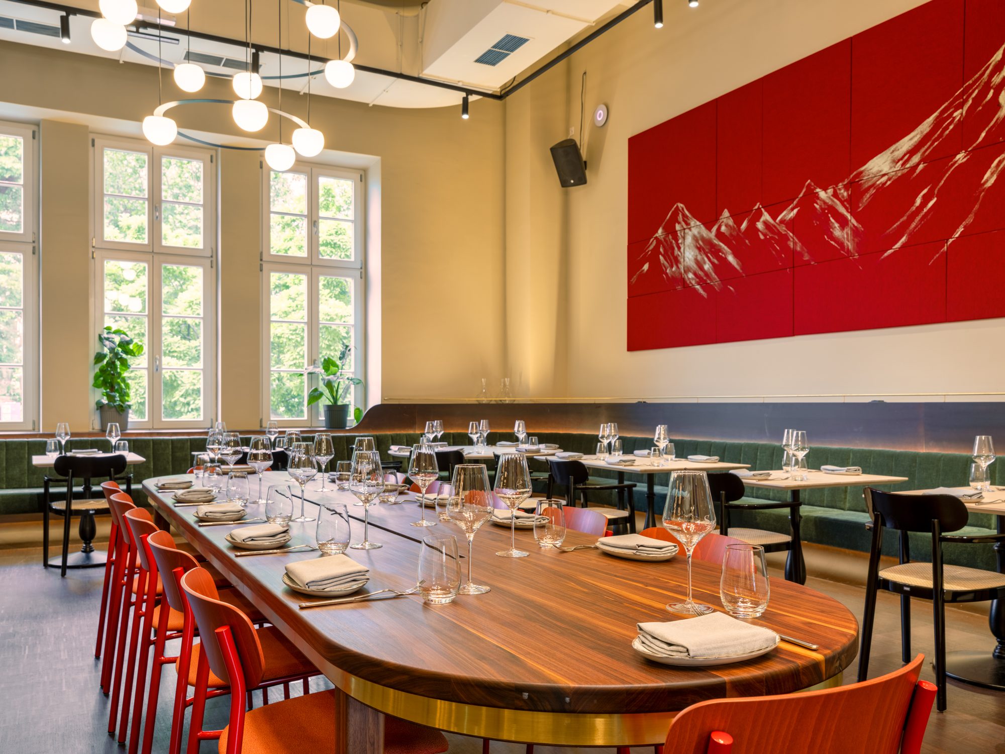 Gedeckte lange Tafel mit Gläsern und roten Stühlen im Salon West